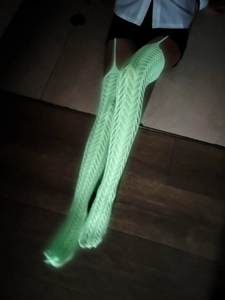Gros plan de bas résille vert fluo avec motif évidé en V brillant dans le noir