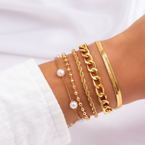 Detail of 5-piece gold bracelet set with pearls and snake chain on model wrist