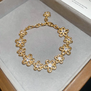 Detailed shot of gold hollow flower bracelet with sparkling zircons and lobster clasp