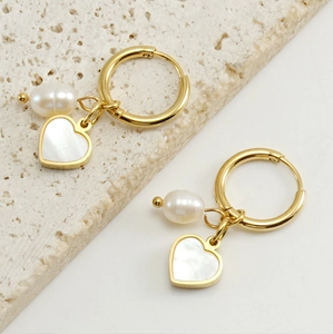 Détail de créoles dorées à l'or 18 carats avec pendentif cœur en nacre et perle