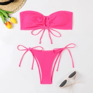 Flat lay of bright pink textured bandeau bikini with tie-front detail and side-tie bottom