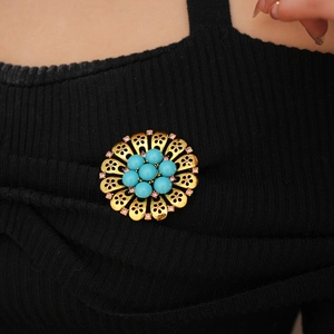 Detailed close-up of a vintage hollow flower brooch with turquoise beads on black fabric