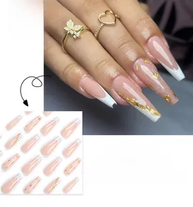 Détail de faux ongles ballerine longs avec pointes blanches et touches dorées