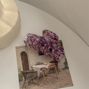 Macro shot of large acetate hair claw with purple marble pattern on a vintage postcard