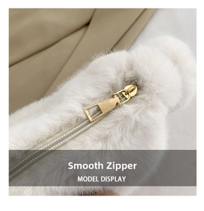 Detailed close-up of smooth gold metal zipper on white faux fur shoulder bag