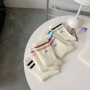 Detail view of cotton crew socks with athletic stripes and Smile embroidery on a table