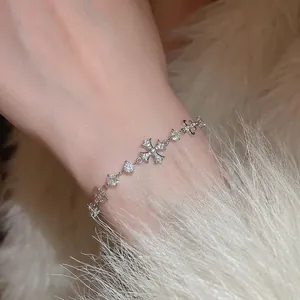 Delicate silver zircon cross bracelet with fleur-de-lis elements on female wrist