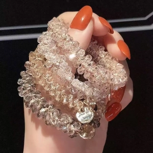 Sparkling crystal bead hair tie set with metal pendant worn on wrist as a stylish bracelet