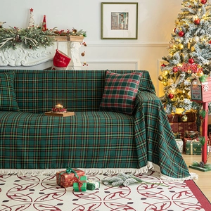 Green and red plaid Christmas sofa cover with white tassels in a festive living room