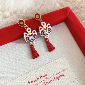 Gros plan détaillé sur les boucles d'oreilles lion chinois avec pompons en soie rouge