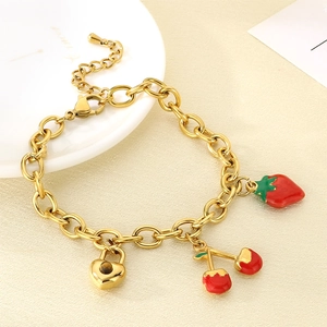 Détail du bracelet doré avec breloques cerise, fraise et cadenas en cœur