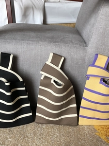 Close-up of three knitted tote bags in striped patterns including black, brown, and yellow