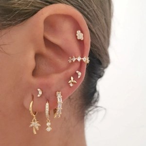 Close-up of golden geometric stud earrings set with sparkling cubic zirconia on ear