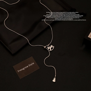Detailed view of silver lariat necklace with rocking horse and money bag pendants
