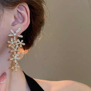Detail of elegant gold flower tassel earrings with zircons worn by a model