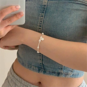 Detailed view of a minimalist 925 silver beaded bracelet with a round pendant on wrist