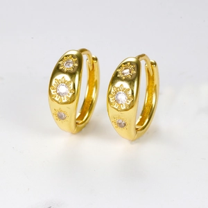Detail view of golden hoop earrings with embossed sunburst pattern and zircon stones