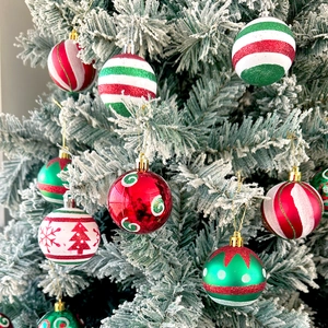 Close-up of decorative Christmas balls with snow patterns hanging on a snowy Xmas tree