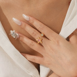 Close-up of gold star open ring with pink star and clear zircon on a woman's finger