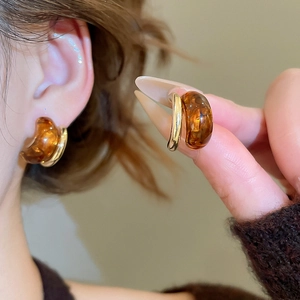 Detail of amber resin tiger eye geometric drop earrings with gold metal accents
