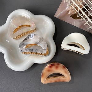Elegant set of four acetate hair claws in leopard and marble patterns on a ceramic plate