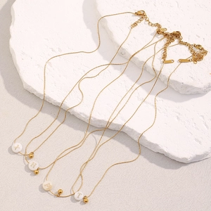 Macro detail of 18K gold plated necklaces with white letter pendants on stone
