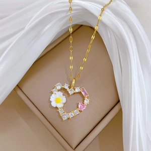 Detail der goldenen Herzanhänger mit eingelegten Gänseblümchen und rosa Edelsteinen