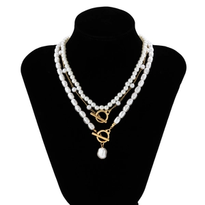 Close-up of baroque pearl necklace layers with a golden toggle clasp on a black bust