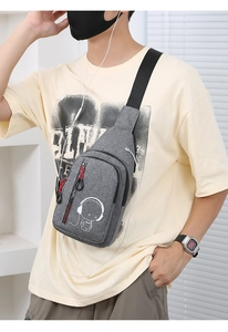 Detail of grey crossbody bag with astronaut graphic, headphone port and red zipper pulls