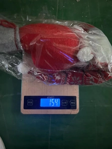 Detailed view of red Christmas faceless doll decoration weighing 154g on a digital scale