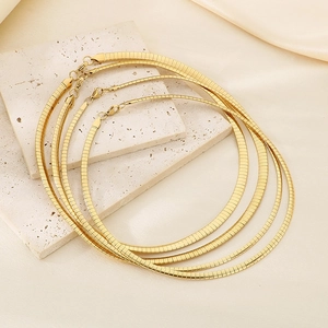 Detail of four golden herringbone chains in various lengths on beige stone display boards