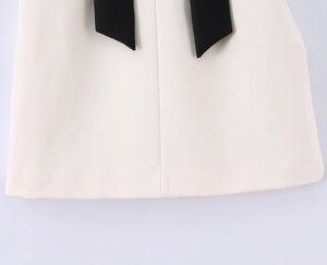 Détail du tissu blanc cassé avec des rubans noirs décoratifs sur un haut bustier