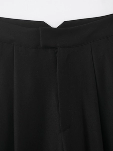 Détail du pantalon plissé noir à taille haute avec texture de tissu sergé premium