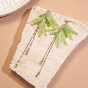 Detail view of long tassel earrings with green acrylic bamboo leaves and silver metal chains