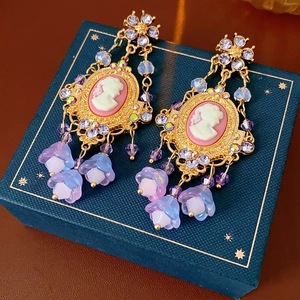 Detail of vintage gold earrings with pink cameo flower tassels and colorful crystals