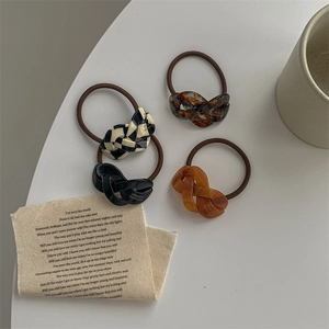 Detail of four handmade elastic hair ties in checkered, amber, black, and orange colors