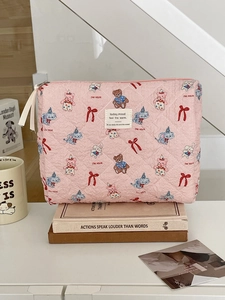 Detail of pink quilted cosmetic bag with cute cartoon doll patterns and metal zipper