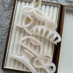 Detailed set of 5 clear white resin hair claws in various shapes on beige velvet