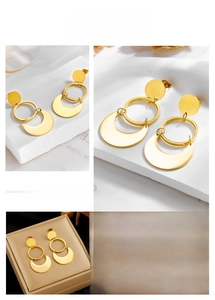 Detail of gold geometric hoop earrings with solid crescent drop on a stone base
