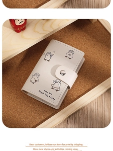 Detail of light gray faux leather card holder with cute penguin illustrations and snap button