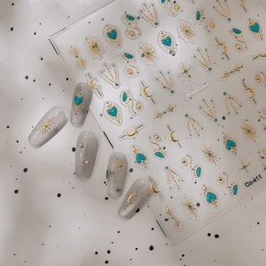 Golden celestial nail stickers with turquoise star and moon patterns on cat eye nails
