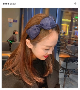 Close-up of a navy blue glitter bow headband worn by a model in a cafe setting