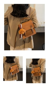 Brown leather vintage-style backpack with plush charm detail shown in lifestyle setup