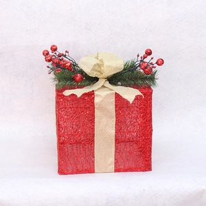 Red mesh Christmas gift box with gold ribbon and pine needles on a white background
