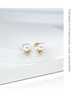 Macro detail of gold plated pearl earrings with zircon stones and shiny finish