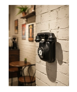 Close-up of vintage wall-mounted rotary telephone on white brick in a retro bar