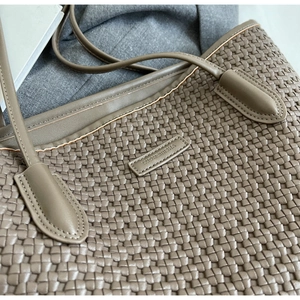 Close-up of brown woven texture PU leather tote bag with metallic brand logo detail