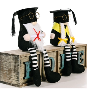 Detail of graduation gnomes with black caps and gold glasses on a rustic wooden box