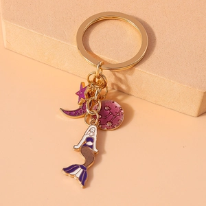 Detail of gold keychain with purple enamel mermaid, moon, star, and zodiac charms
