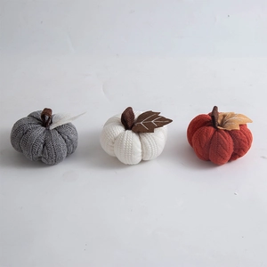 Three knitted pumpkins in gray, white, and orange with decorative stems for fall decor